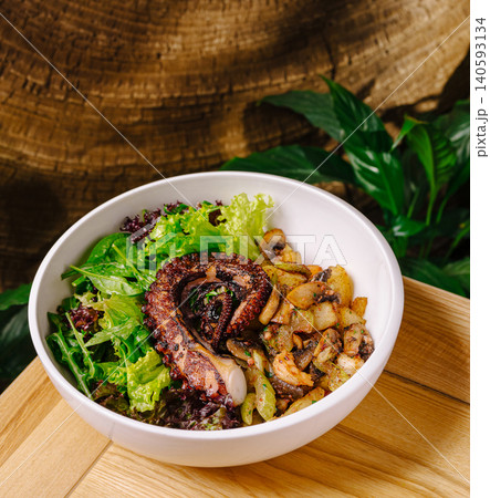 Grilled octopus bowl with fresh salad and sauteed mushrooms on wood Grilled octopus bowl with fresh salad and sauteed mushrooms on wood 140593134