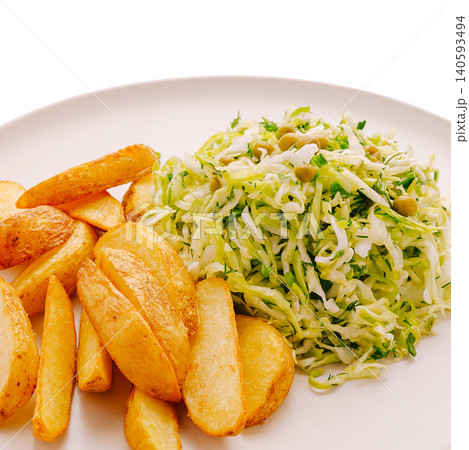 Healthy dish with potato wedges and fresh cabbage salad on white plate Healthy dish with potato wedges and fresh cabbage salad on white plate 140593494