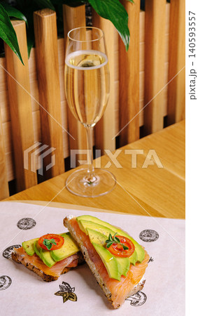 Enjoying a light meal with avocado, salmon, and sparkling drink at a cozy table Enjoying a light meal with avocado, salmon, and sparkling drink at a cozy table 140593557