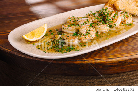 Shrimp served with garlic sauce and lemon on a white plate at a restaurant Shrimp served with garlic sauce and lemon on a white plate at a restaurant 140593573