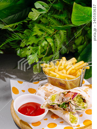 Delicious wrap with fries and sauce served in a green setting Delicious wrap with fries and sauce served in a green setting 140593637