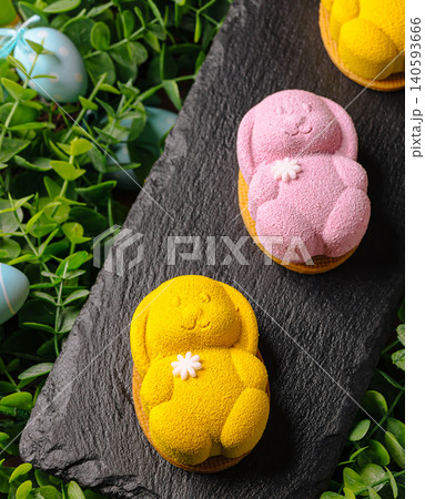 Easter treats on a black plate with green leaves and colored eggs around Easter treats on a black plate with green leaves and colored eggs around 140593666