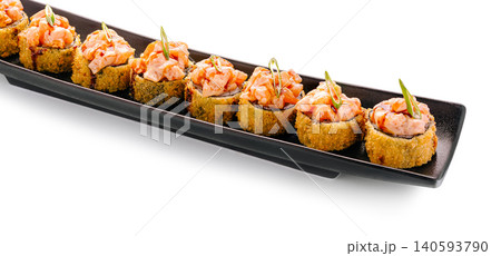 Sushi rolls with salmon and crispy coating on a long black plate 140593790