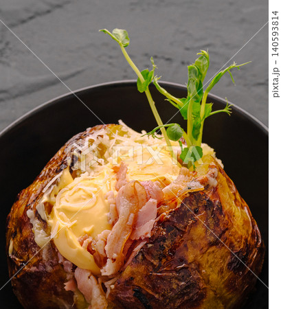 Delicious baked potato with toppings served in a black bowl Delicious baked potato with toppings served in a black bowl 140593814