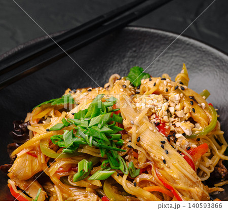 Delicious chicken noodles with vegetables in a black bowl with chopsticks Delicious chicken noodles with vegetables in a black bowl with chopsticks 140593866