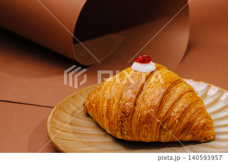 Croissant with cream and cherry on a plate in a simple setting 140593957