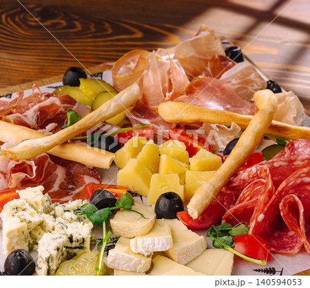 Cheese and meat platter with olives and breadsticks on a wooden table Cheese and meat platter with olives and breadsticks on a wooden table 140594053