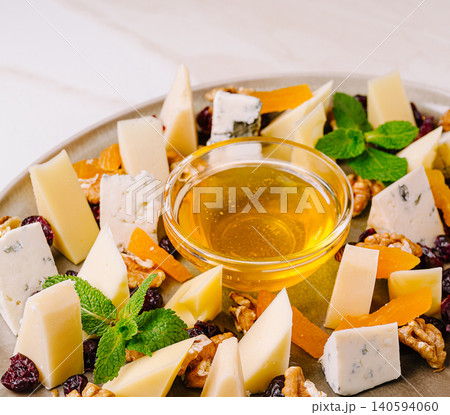 Cheese and fruit platter with nuts and honey in a dining setting Cheese and fruit platter with nuts and honey in a dining setting 140594060