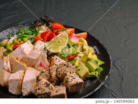 Fresh salad with grilled chicken and avocado served on a black plate Fresh salad with grilled chicken and avocado served on a black plate 140594062