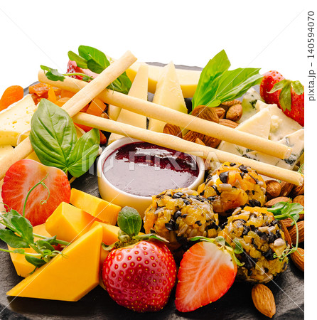 Different types of cheese, fruits, and snacks arranged on a black platter Different types of cheese, fruits, and snacks arranged on a black platter 140594070