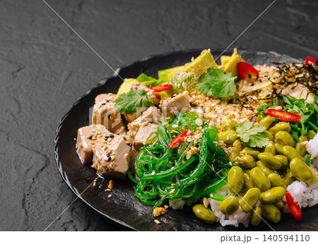 Delicious healthy meal with tofu, seaweed, and beans served on a black plate 140594110