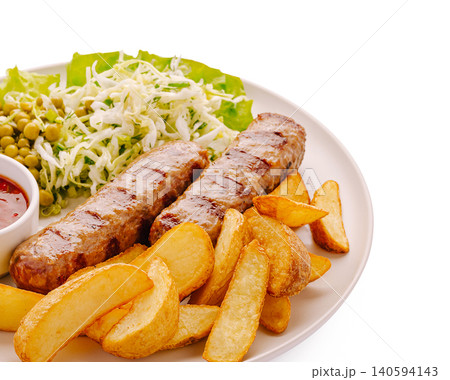 Grilled sausages with potato wedges and salad on a white plate served Grilled sausages with potato wedges and salad on a white plate served 140594143