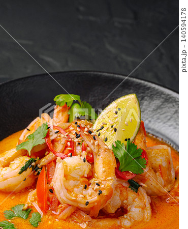 Shrimp dish with lime and cilantro served in black bowl on dark table 140594178