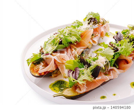 Fresh salad with prosciutto and greens served on a plate 140594180