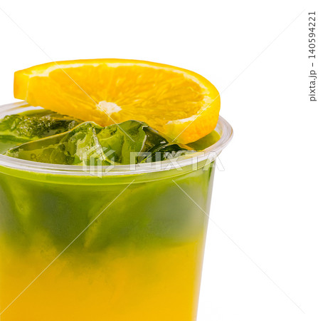 Refreshing drink with layers of orange and green in clear cup served cold 140594221
