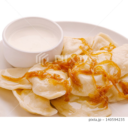 Dumplings with sour cream and fried onions served on a white plate Dumplings with sour cream and fried onions served on a white plate 140594235