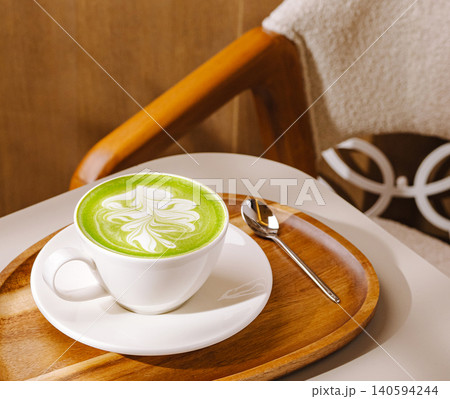 Matcha tea sits on a wooden tray beside a soft chair in a cozy cafe Matcha tea sits on a wooden tray beside a soft chair in a cozy cafe 140594244
