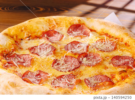Pizza sits on a round wooden board in a restaurant on a sunny day Pizza sits on a round wooden board in a restaurant on a sunny day 140594250