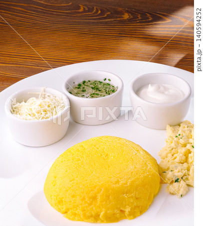 Tasty cornmeal dish with sauces on a wooden table 140594252