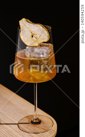 Cocktail served on a wooden table with dried fruit garnish in a bar scene 140594259