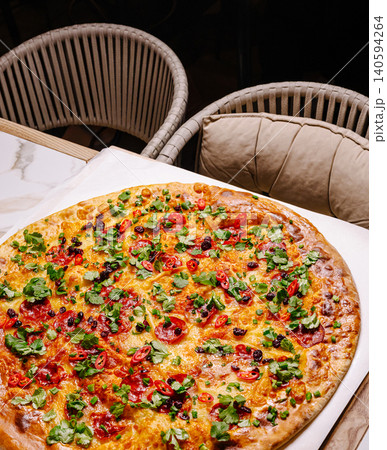 Giant pizza on a table with chairs in a cozy restaurant setting Giant pizza on a table with chairs in a cozy restaurant setting 140594264
