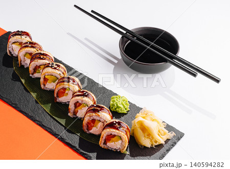 Sushi served on a black plate with chopsticks and side condiments 140594282