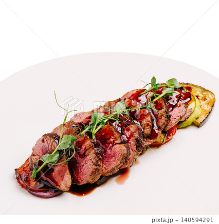Cooked meat served on a plate with garnishes and sauce 140594291
