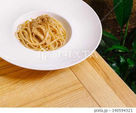 Spaghetti on a white plate placed on a wooden table with green plants Spaghetti on a white plate placed on a wooden table with green plants 140594321