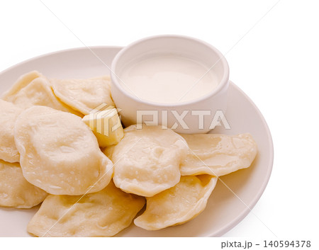 Dumplings served with sour cream on a white plate at a kitchen table Dumplings served with sour cream on a white plate at a kitchen table 140594378