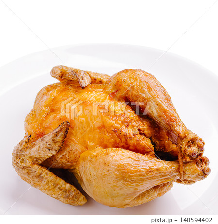 Whole chicken cooked and placed on a white plate in kitchen setting 140594402