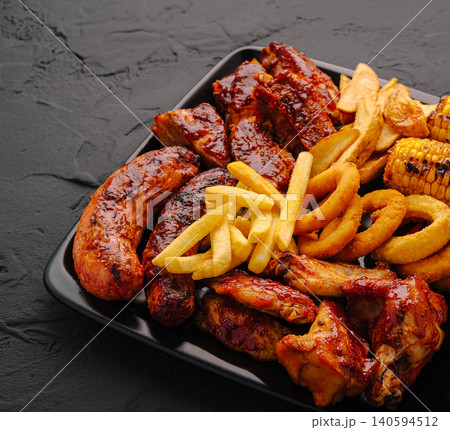 Grilled meat platter served with fries and corn on a black plate Grilled meat platter served with fries and corn on a black plate 140594512