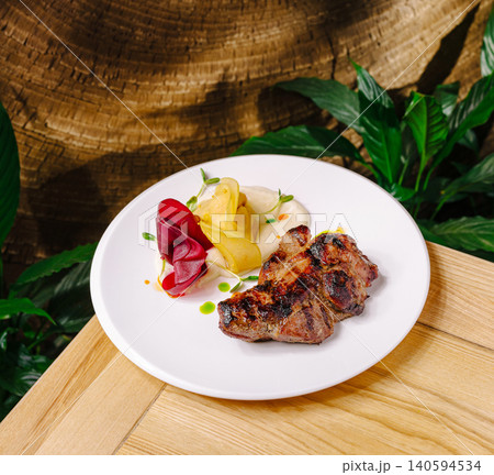 Grilled meat dish served with colorful vegetables on a wooden table Grilled meat dish served with colorful vegetables on a wooden table 140594534