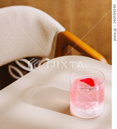 Drink sits on a table next to a chair in a quiet space during the day Drink sits on a table next to a chair in a quiet space during the day 140594540