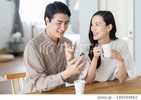 リビングでスマホを見るミドルの夫婦 リビングでスマホを見るミドルの夫婦 140594662