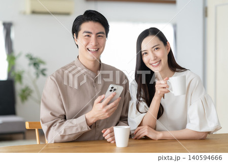 リビングでスマホを見るミドルの夫婦 リビングでスマホを見るミドルの夫婦 140594666