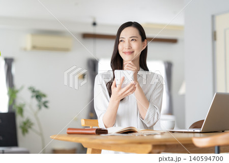 リビングで家計簿をつける女性 リビングで家計簿をつける女性 140594700