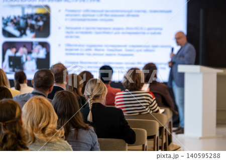 Business presentation with attentive audience in conference room, speaker delivering talk Business presentation with attentive audience in conference room, speaker delivering talk 140595288