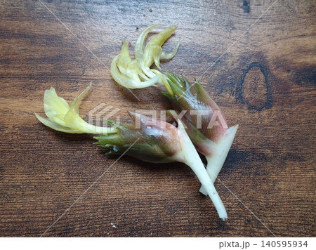 木目背景に置かれた、薄黄色い花が咲いた新鮮なミョウガの花蕾 木目背景に置かれた、薄黄色い花が咲いた新鮮なミョウガの花蕾 140595934