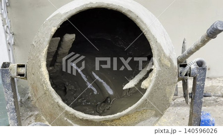 Close up of concrete being mixed inside a cement mixer. The rotating drum blends the materials together, creating smooth and consistent mixture prepared for construction work on building site Close up of concrete being mixed inside a cement mixer. The rotating drum blends the materials together, creating smooth and consistent mixture prepared for construction work on building site 140596026