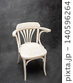 Elegant white wooden chair with curved arms and slatted backrest, set against a textured dark background, showcasing minimalist design and craftsmanship 140596264