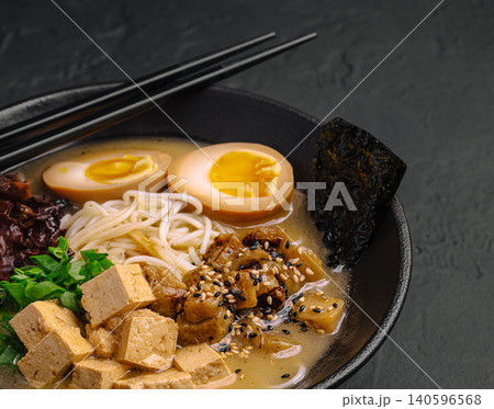 Japanese ramen noodles with tofu, egg, and seaweed in black bowl 140596568