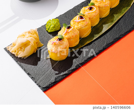 Baked sushi rolls with ginger and wasabi on slate Baked sushi rolls with ginger and wasabi on slate 140596606