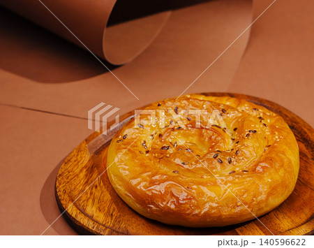 Spiraling burek pastry with sesame seeds on wooden plate Spiraling burek pastry with sesame seeds on wooden plate 140596622