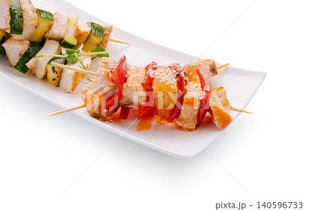 Chicken and salmon skewers with grilled vegetables on white plate Chicken and salmon skewers with grilled vegetables on white plate 140596733
