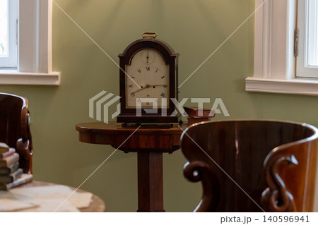 An antique mantel clock sits on a polished wooden side table 140596941