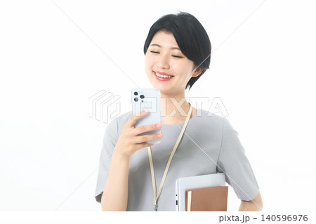 白背景でスマホ画面を見て微笑む資料を持った若い女性 白背景でスマホ画面を見て微笑む資料を持った若い女性 140596976