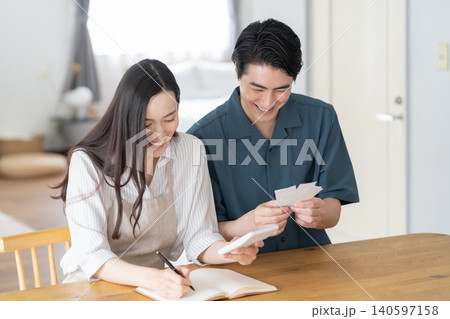 リビングで家計簿をつけるミドルの夫婦 140597158