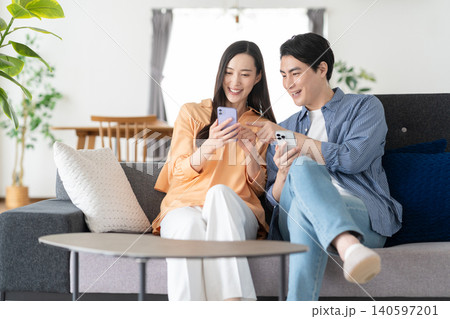リビングでスマホを見るミドルの夫婦 140597201