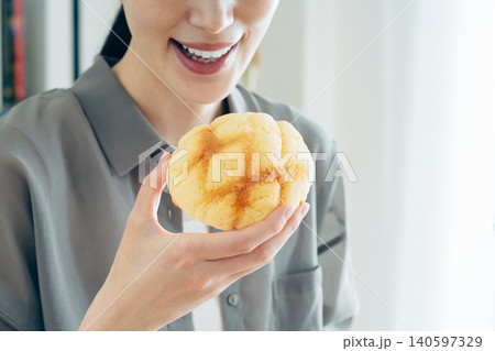 家でメロンパンを食べる若い女性 140597329