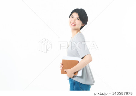 白背景で資料を抱えて振り返る笑顔の若い女性 白背景で資料を抱えて振り返る笑顔の若い女性 140597979